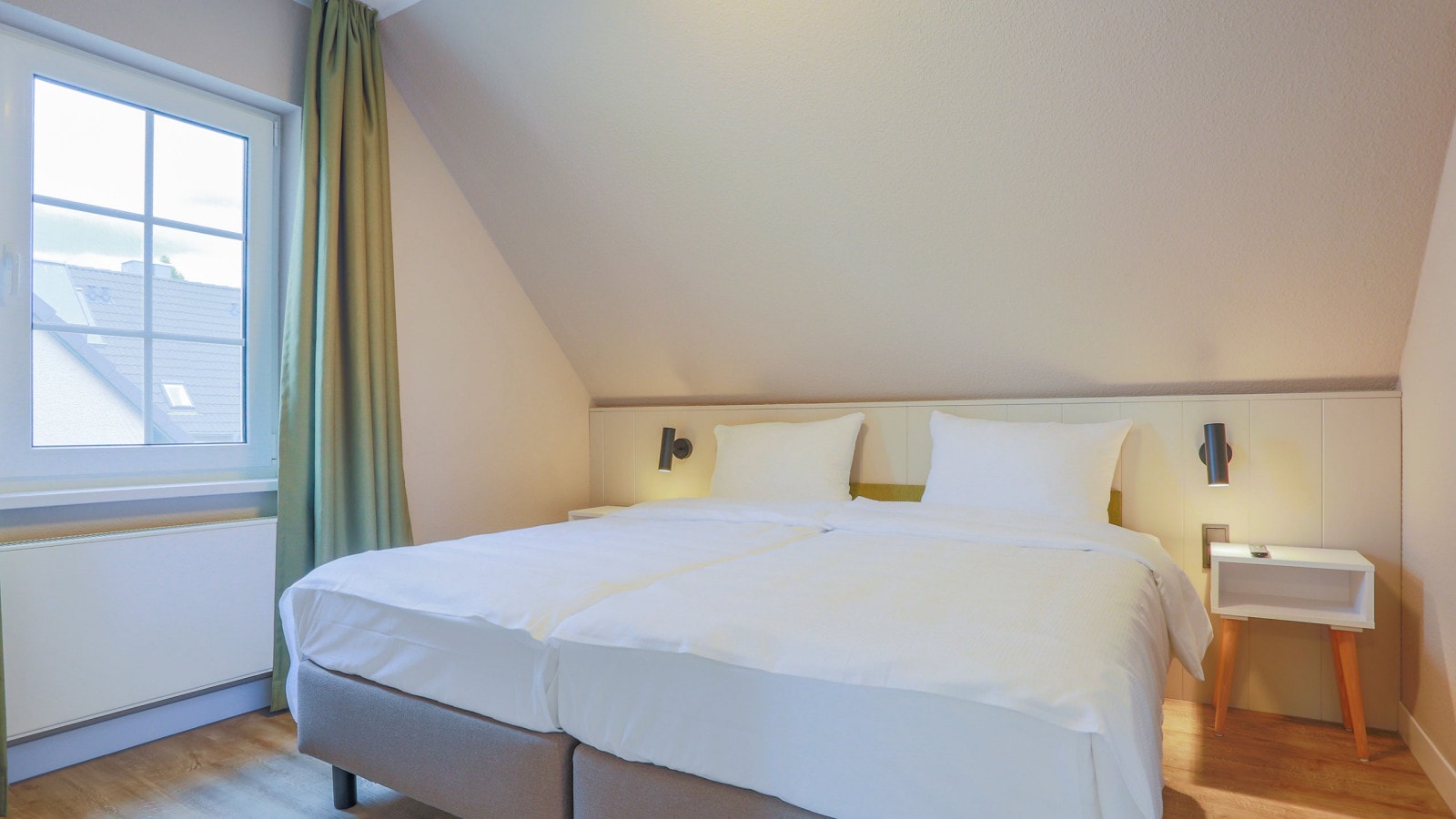 Gemütliches Doppelbett in einem Schlafzimmer mit großen Fenstern